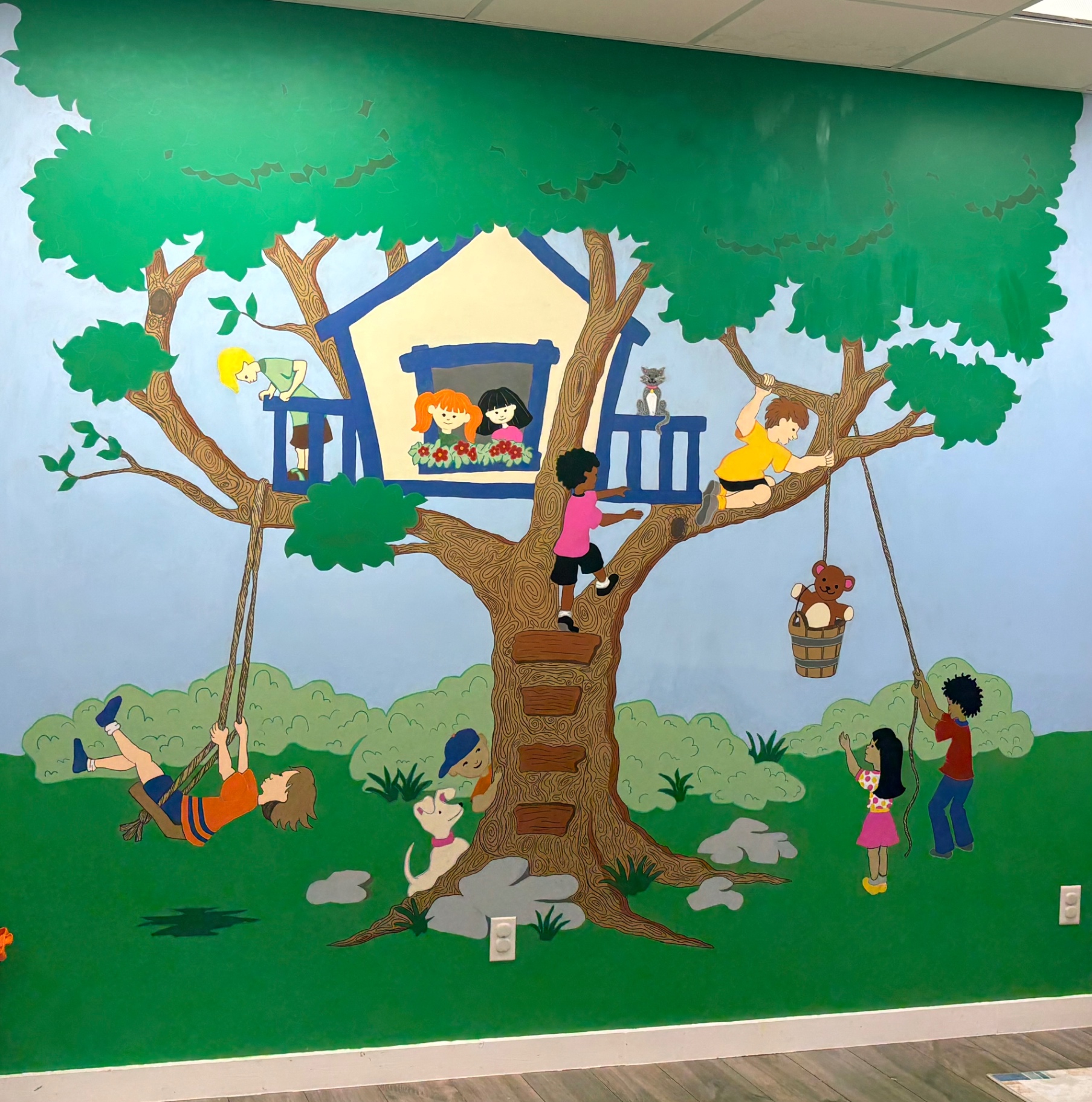 Colorful treehouse mural at Angel's Abode showing children playing in a welcoming, safe environment.