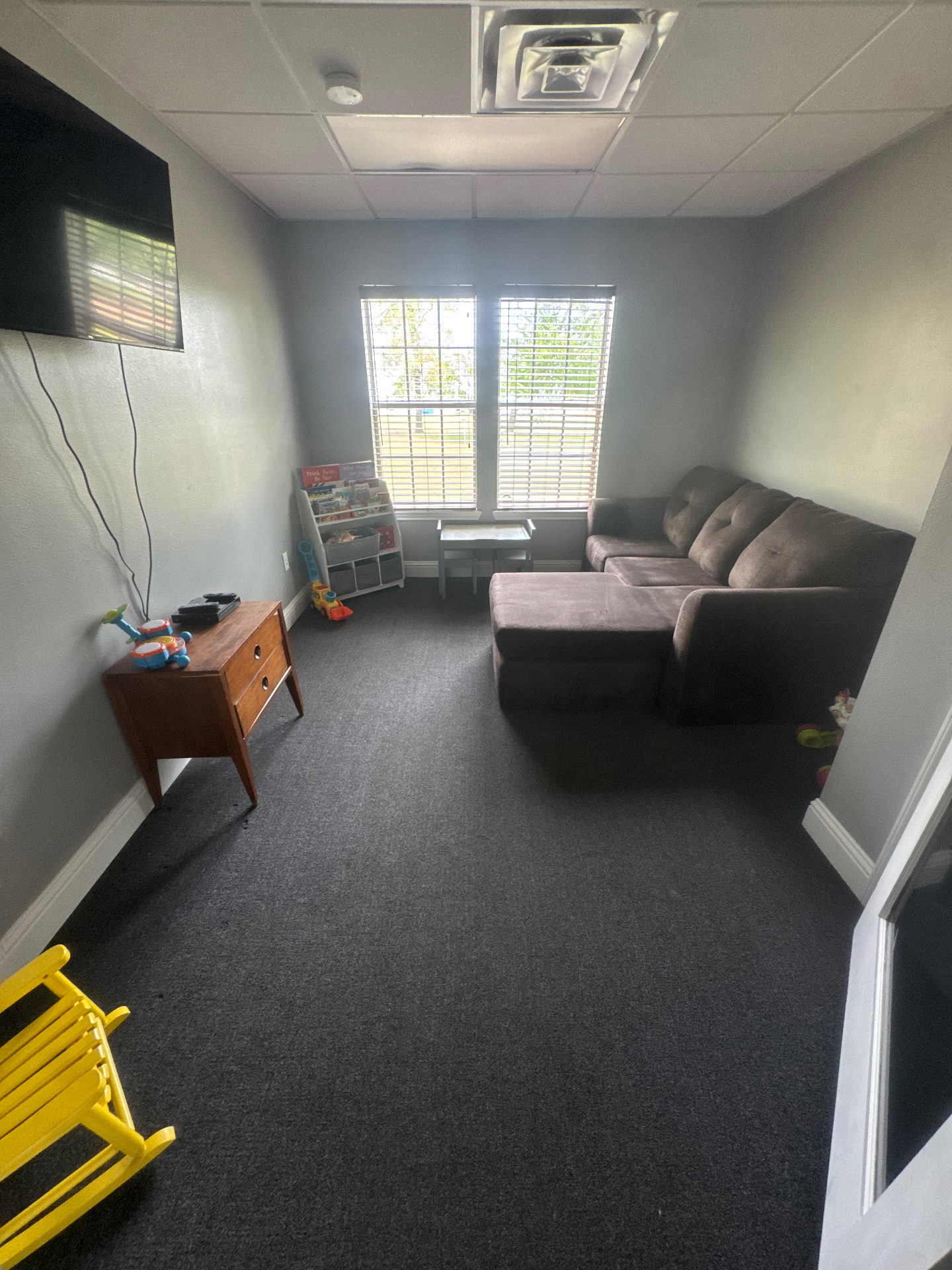 Quiet family lounge with sectional sofa and children's books at Angel Watch Supervision.